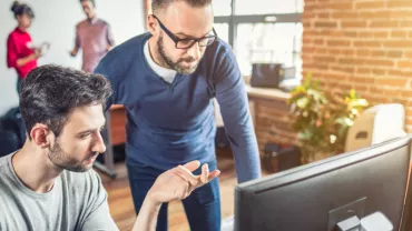 Dos personas trabajando en un ordenador en una oficina moderna.