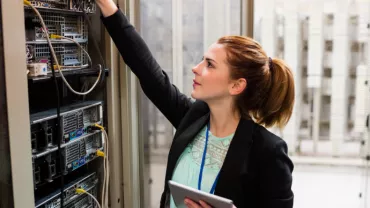 Persona revisando equipos en una sala de servidores