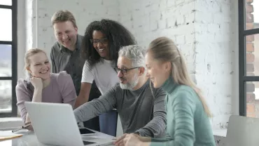 Grupo de personas trabajando juntos frente a un portátil.