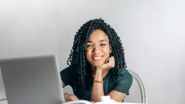 Persona sonriendo frente a una computadora portátil