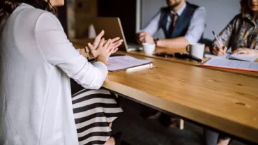 Una mujer durante una entrevista de trabajo con otras dos personas en un entorno laboral 