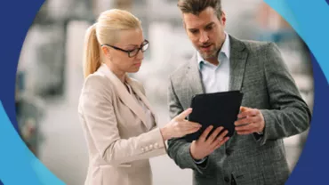 Dos personas en ropa formal revisan una tableta.