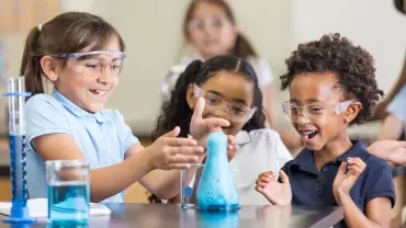 Niños en clase de ciencias sorprendidos por una reacción química.