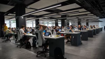 Oficina con personas trabajando en computadoras portátiles.