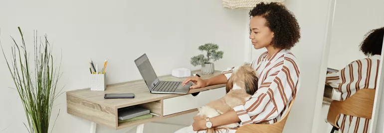 Una mujer trabajando a distancia desde su oficina en casa, utilizando un ordenador portátil, disfrutando de la flexibilidad laboral.